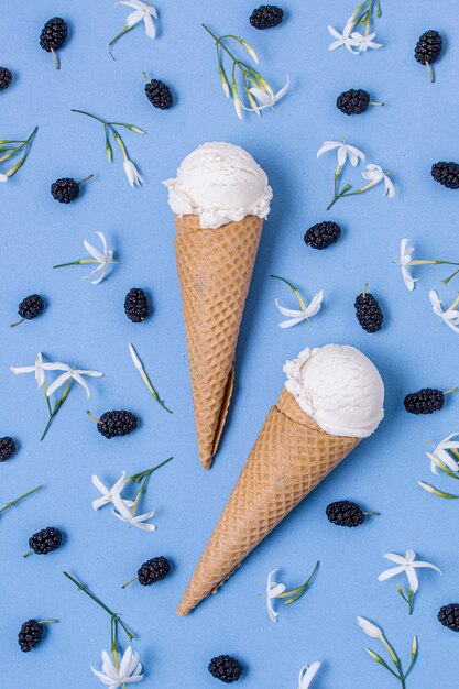 Cornets de crème glacée à la vanille blanche entourés de baies et de fleurs