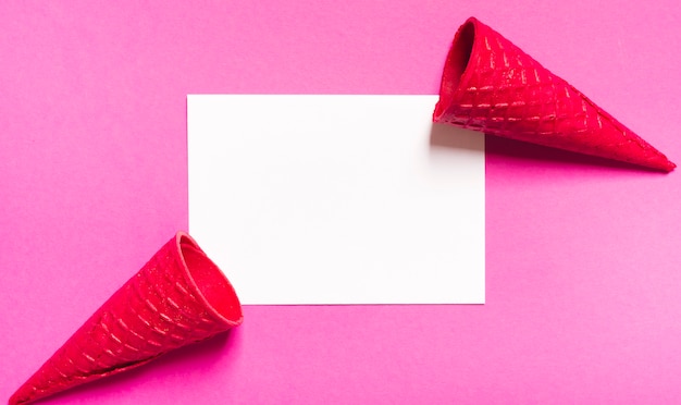 Cornets de glace croustillants et feuille blanche sur fond rose