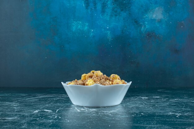 Cornflakes délicieux dans un bol, sur la table bleue.