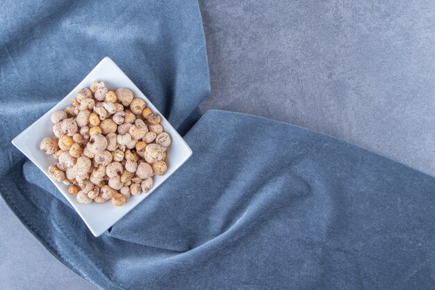 Cornflakes avec muesli dans un bol sur un morceau de tissu, sur la table en marbre.