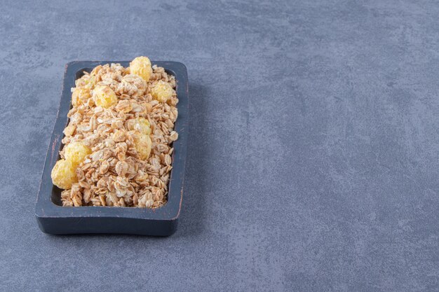 Cornflakes savoureux dans une planche, sur la table en marbre.