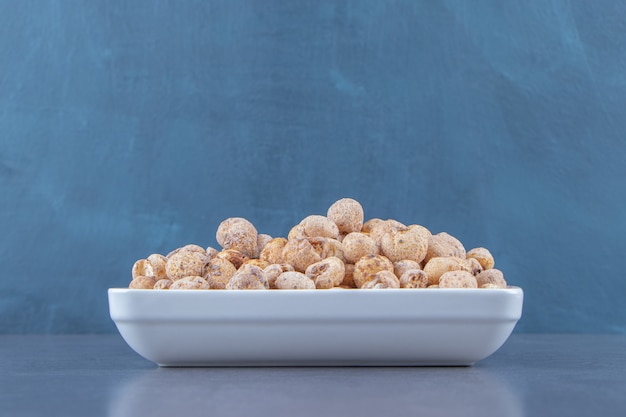 Cornflakes sucrés avec du muesli dans un bol, sur fond de marbre.