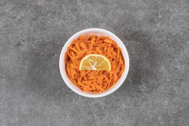 Cornichon aux carottes hachées dans un bol blanc avec une tranche de citron.