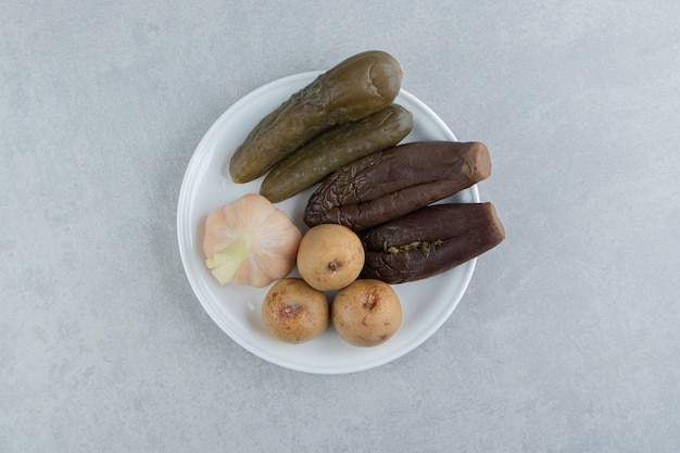 Cornichons assortis placés sur une assiette blanche.