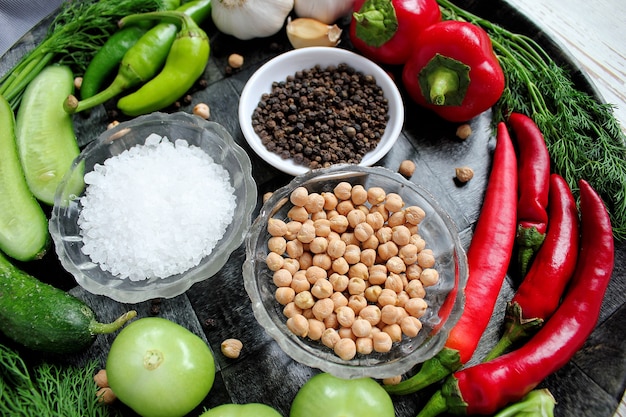 Cornichons sur table en bois blanc avec poivrons verts et rouges, fenouil, sel, grains de poivre noirs, ail, pois, gros plan, concept santé, vue de dessus, vue à plat