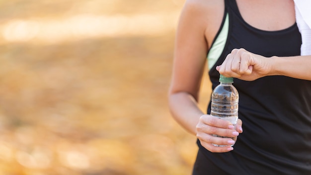 Corps sportif tenant une bouteille d'eau