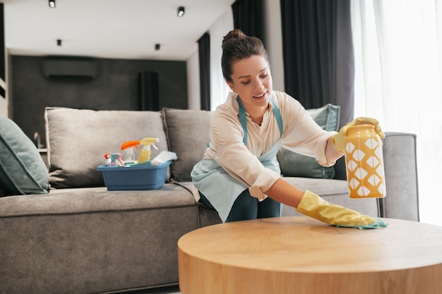 Corvées. Une femme nettoyant une table surfcase avec désinfecteur