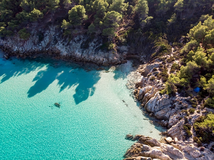 Photo gratuit côte de la mer égée avec eau transparente bleue, verdure autour, rochers, buissons et arbres, vue depuis le drone grèce