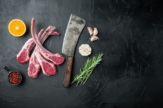 Côtelette d'agneau fraîche. ensemble de steak de viande biologique, avec ingrédients orange carotte, herbes, sur table en pierre noire, vue de dessus à plat
