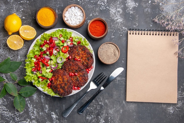 Côtelettes de viande vue de dessus avec salade fraîche et assaisonnements