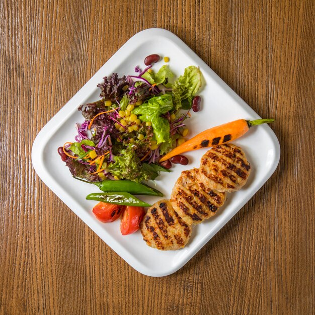 Côtes de filet de poulet avec salade verte et carottes.