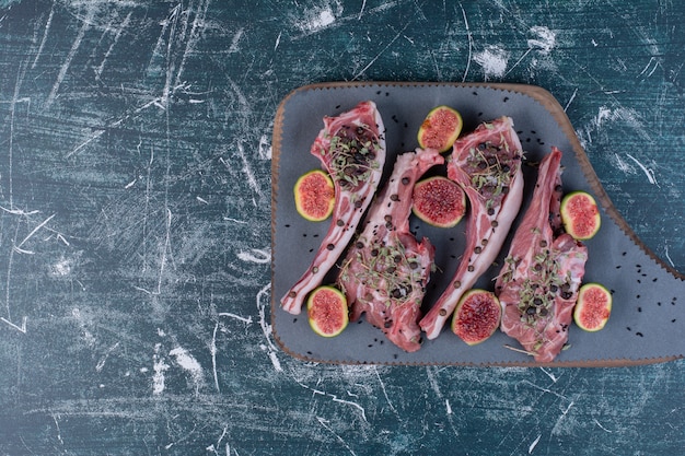 Côtes levées crues en planche de bois avec figues et herbes séchées.