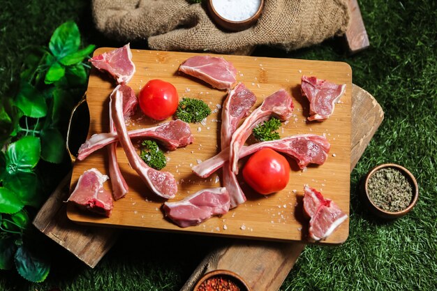 Photo gratuite côtes levées crues sur planche de bois vert sel poivre vue de dessus