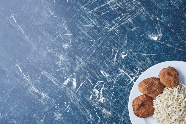 Cotlets de poulet aux nouilles dans une assiette blanche.