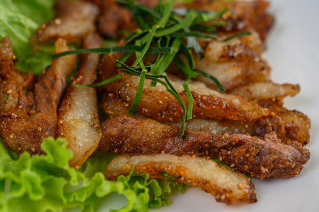 Cou de porc grillé sur une plaque blanche sur une table en bois.