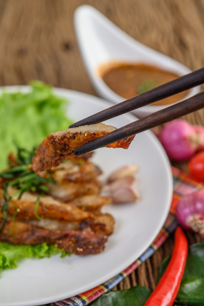 Cou de porc grillé sur une plaque blanche sur une table en bois.