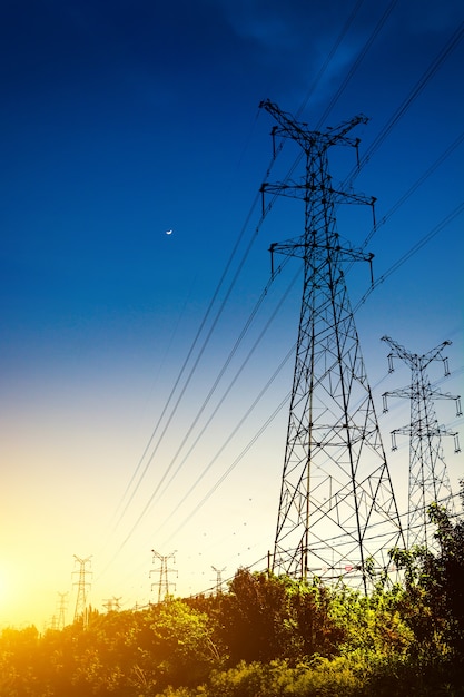 Le coucher du soleil derrière la silhouette des pylônes d&#39;électricité