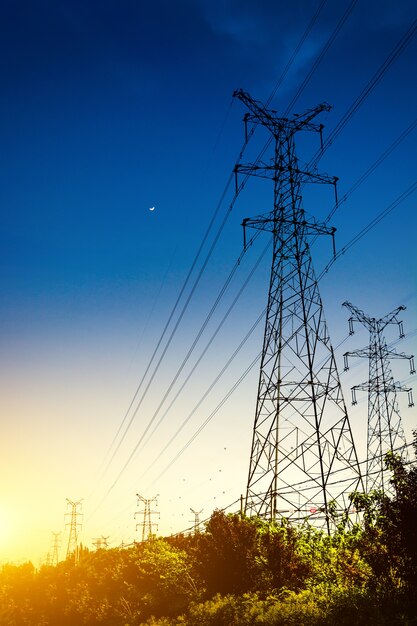 Le coucher du soleil derrière la silhouette des pylônes d&#39;électricité