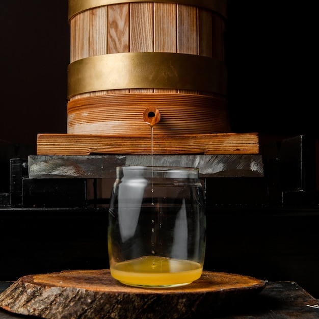 Écoulement d'huile dans la vue latérale du bocal en verre sur une pièce sombre et en bois