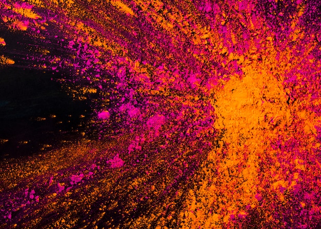 Des couleurs holi mélangées d'orange et de poudre rose sur un fond noir