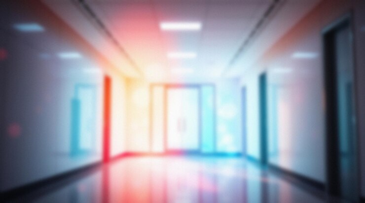 Le couloir flou de l'hôpital la nuit, les lumières colorées, l'espace vide.