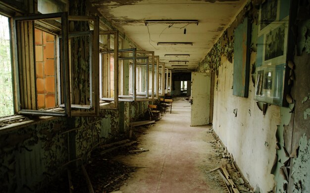 Couloir scolaire abandonné avec fenêtres ouvertes dans la zone de la ville fantôme de radioactivité de Tchernobyl