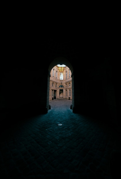 Couloir sombre avec porte voûtée avec vue sur un bâtiment en béton