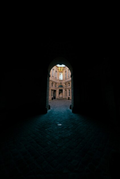 Couloir sombre avec porte voûtée avec vue sur un bâtiment en béton