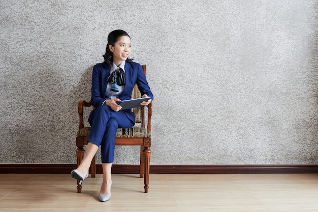 Coup Complet De Femme D'affaires Chic Avec Tablette à La Recherche De La Caméra Assis Dans Une Chaise