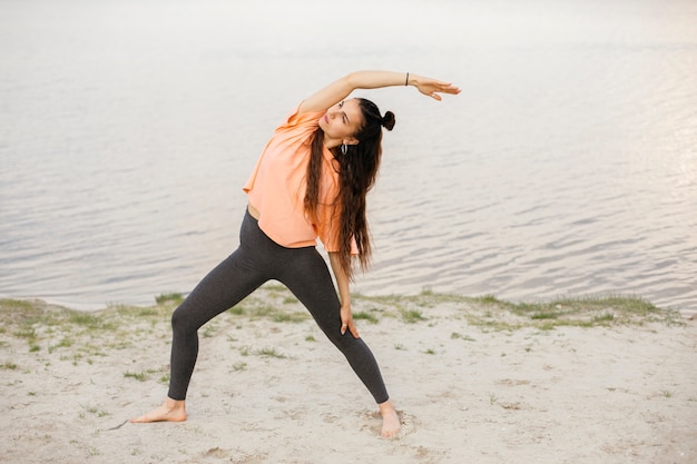 Photo gratuite coup complet fille s'étendant près du lac