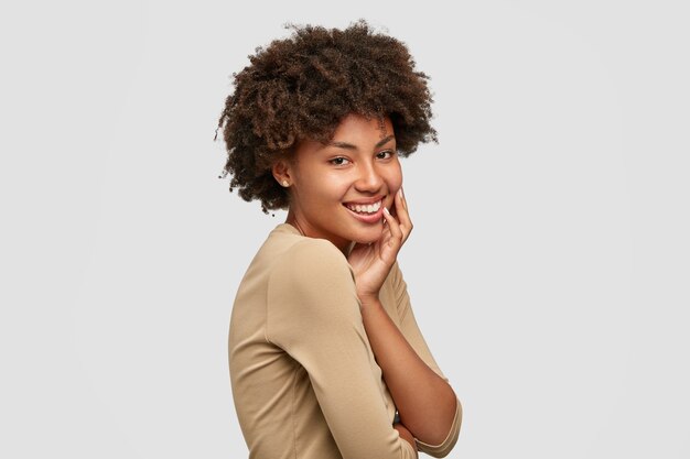 Coup de côté de joyeux jeune mannequin à la peau sombre avec coupe de cheveux afro