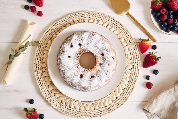 Coup de frais généraux d'un gâteau d'anneau avec des fruits et de la poudre sur un tableau blanc