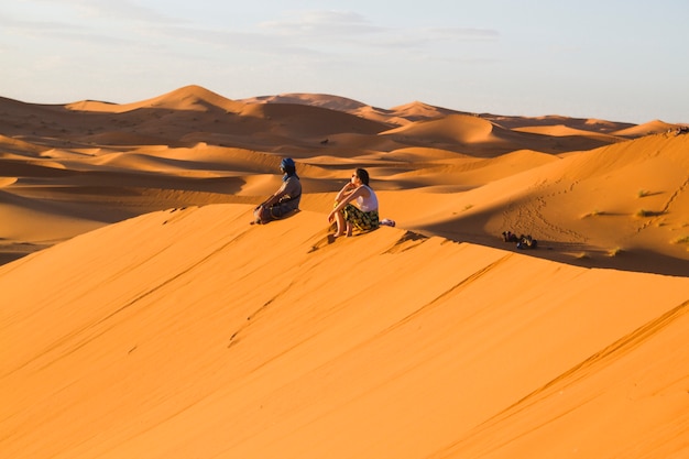 Coup long extrême de deux personnes assises au sommet d&#39;une dune