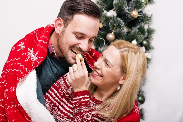 Coup de mise au point peu profonde d'un couple joyeux à côté de l'arbre de Noël