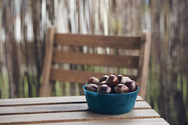 Coup de mise au point sélective de châtaignes dans un bol bleu sur une table en bois