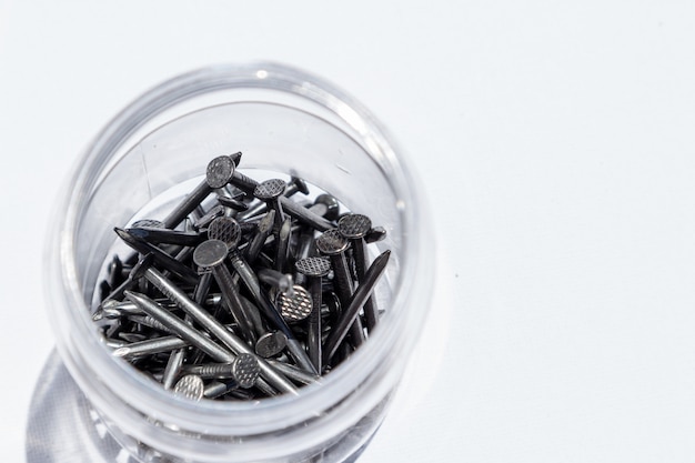 Coup de mise au point sélective de clous métalliques dans un pot avec un fond blanc