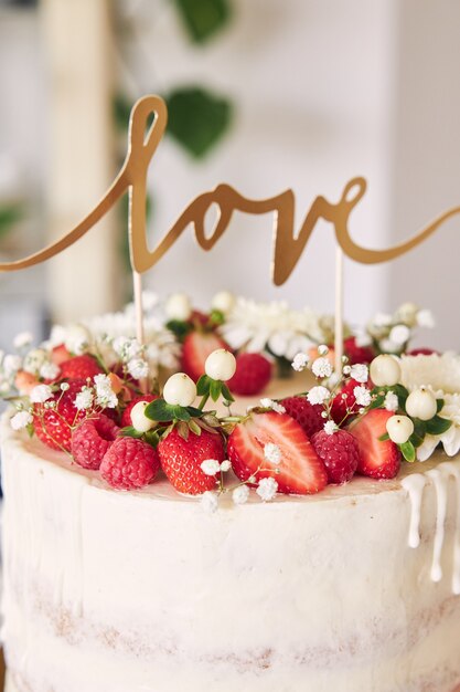 Coup de mise au point sélective de délicieux gâteau de mariage blanc avec des fruits rouges, des fleurs et de gâteau