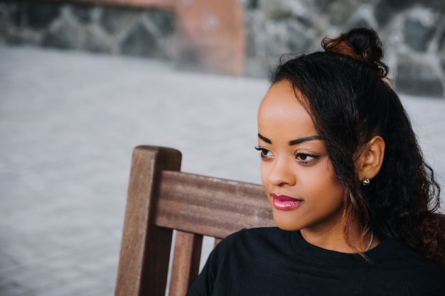 Photo gratuite coup de mise au point sélective d'une femme afro-américaine souriante avec un mur sur l'arrière-plan