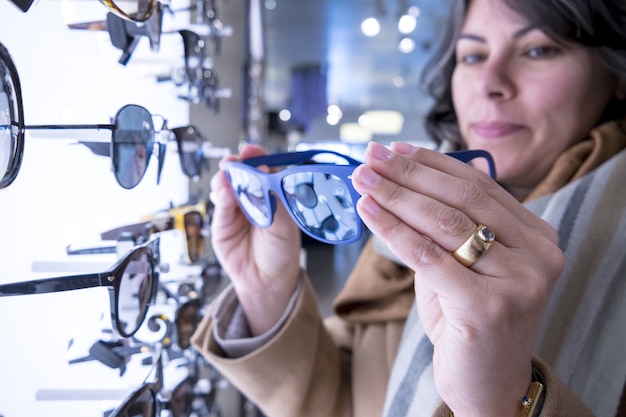 Coup de mise au point sélective d'une femme tenant des lunettes de soleil bleues