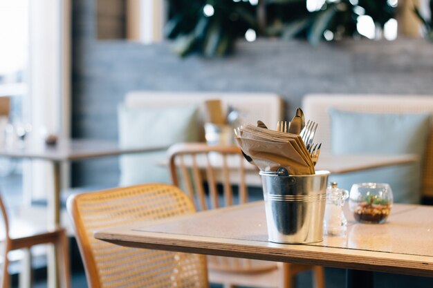 Coup de mise au point sélective d'un seau avec fourchettes et serviettes sur une table de café à la mode