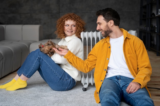 Photo gratuite coup moyen couple assis près du radiateur