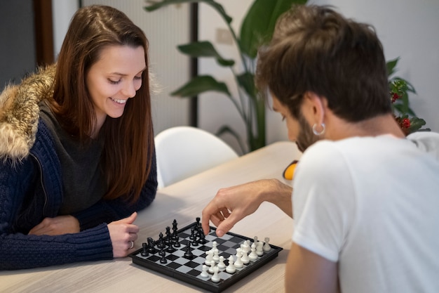 Photo gratuite coup moyen couple heureux jouant aux échecs