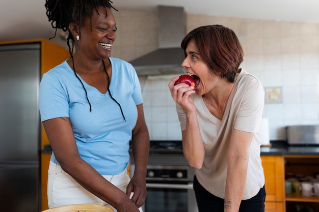 Photo gratuite coup moyen couple de lesbiennes à la maison avec de la nourriture