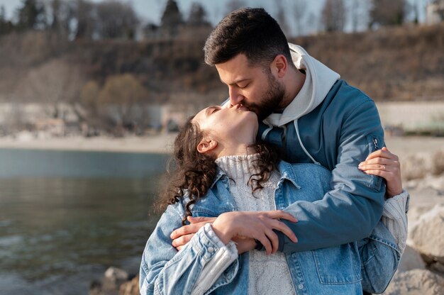 Coup moyen couple s'embrassant au bord de la mer