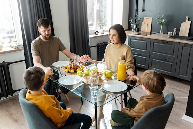 Coup moyen famille chrétienne mangeant ensemble