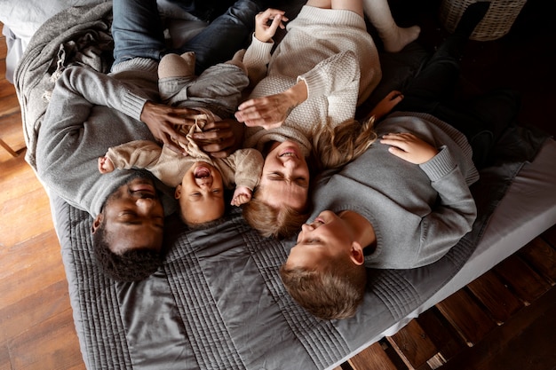 Coup moyen famille heureuse allongée sur le lit