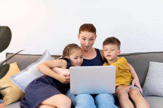 Coup moyen de la famille avec un ordinateur portable sur un canapé