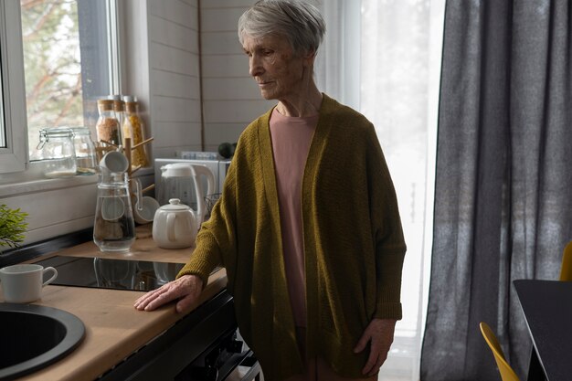 Coup moyen femme âgée solitaire dans la cuisine