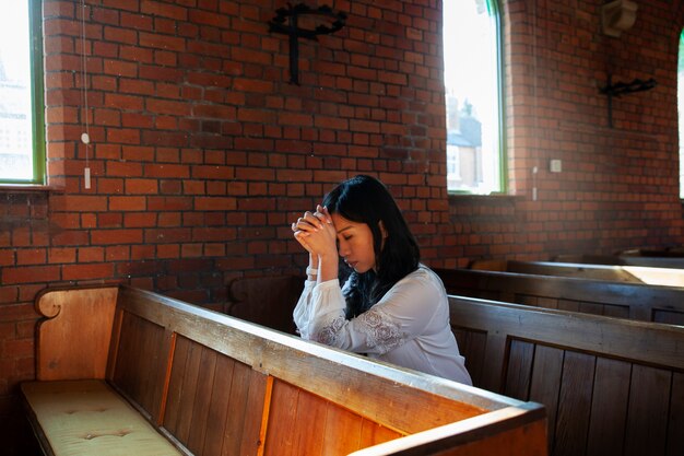 Coup moyen femme chrétienne priant à l'église