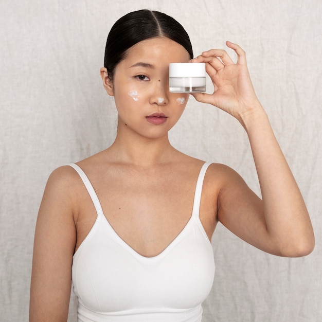Photo gratuite coup moyen femme coréenne posant avec de la crème pour le visage